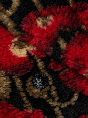 Close-up of the Tristan Sherpa Midi Coat by L'AGENCE, showcasing its textured Italian wool-blend fabric in tan and black with a bold red poppy print, and featuring a black button with an intricate design.