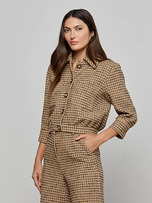 A woman wears the Jia Cropped Tweed Jacket in textured tan with matching high-waisted pants, standing with one hand in her pocket against a plain light gray background.