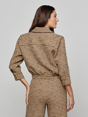 A woman with long brown hair, wearing the Jia Cropped Tweed Jacket with gold buttons on the cuffs and waistband, stands facing away against a plain light gray background. She pairs it with round gold earrings.