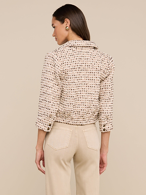 A woman with long brown hair, in gold earrings and light beige pants, models the Jia Cropped Tweed Jacket in beige and brown tweed, standing with her back to the camera against a neutral background.