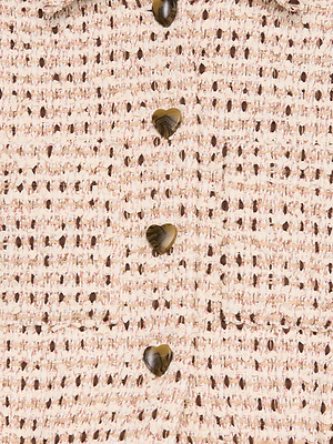 Close-up of cream and light pink woven fabric from the Jia Cropped Tweed Jacket, featuring five marbled brown heart-shaped buttons arranged vertically.