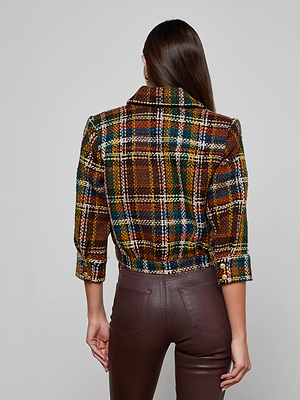 A woman with long brown hair is seen from the back wearing the Jia Cropped Tweed Jacket and high-waisted brown leather pants against a plain gray background.