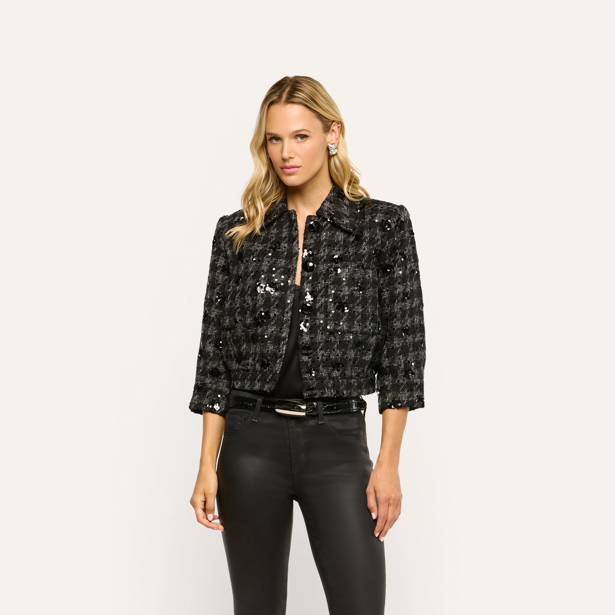 The Jia Sequined Tweed Jacket is a cropped black-and-white tweed piece worn over a black top and black pants.