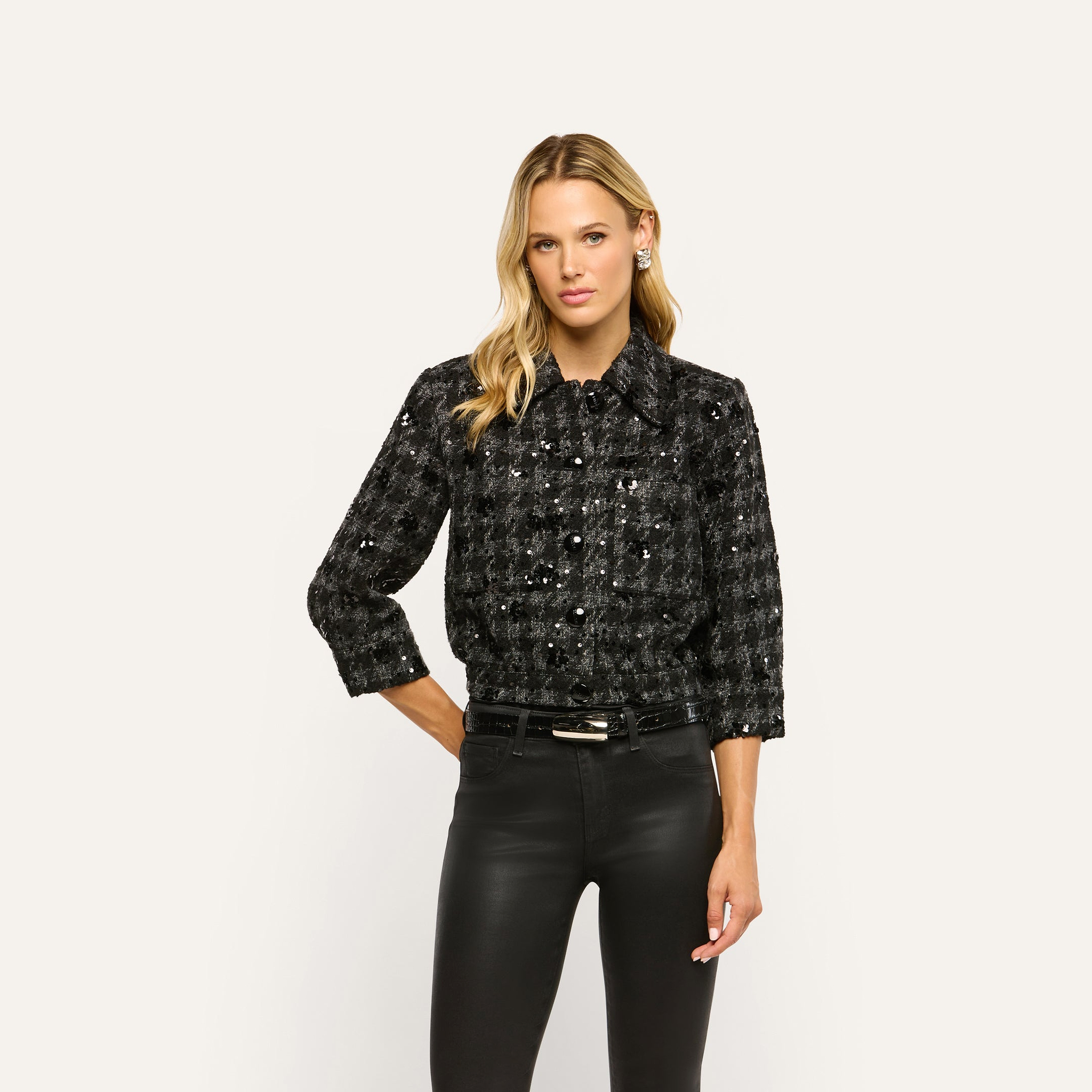 A woman wears a black and gray Jia Sequined Tweed Jacket with sequin embellishments and black trousers.