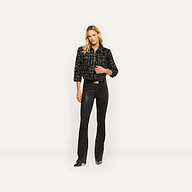 A woman wearing a black Jia Sequined Tweed Jacket over a black top and black flared trousers.