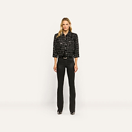 A woman wearing a black Jia Sequined Tweed Jacket, a black shirt, and slim black pants.