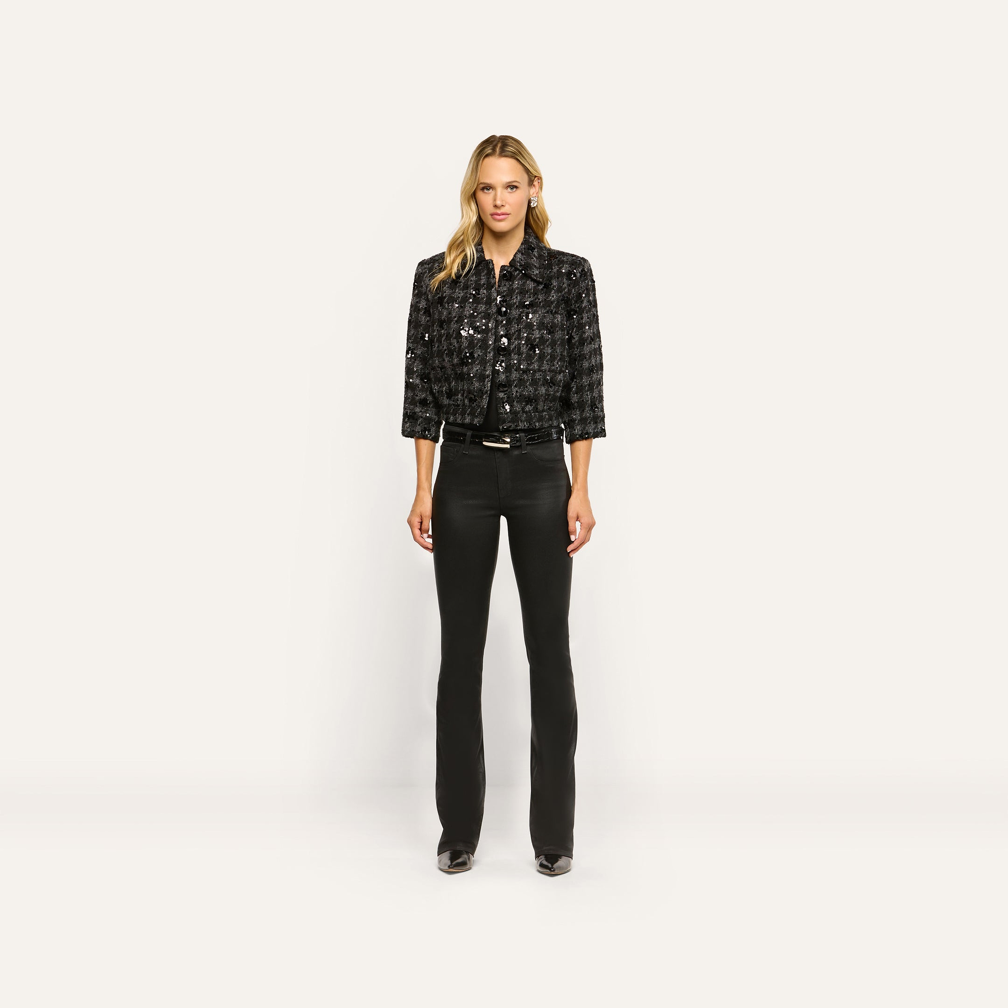 A woman wearing a black Jia Sequined Tweed Jacket, a black shirt, and slim black pants.