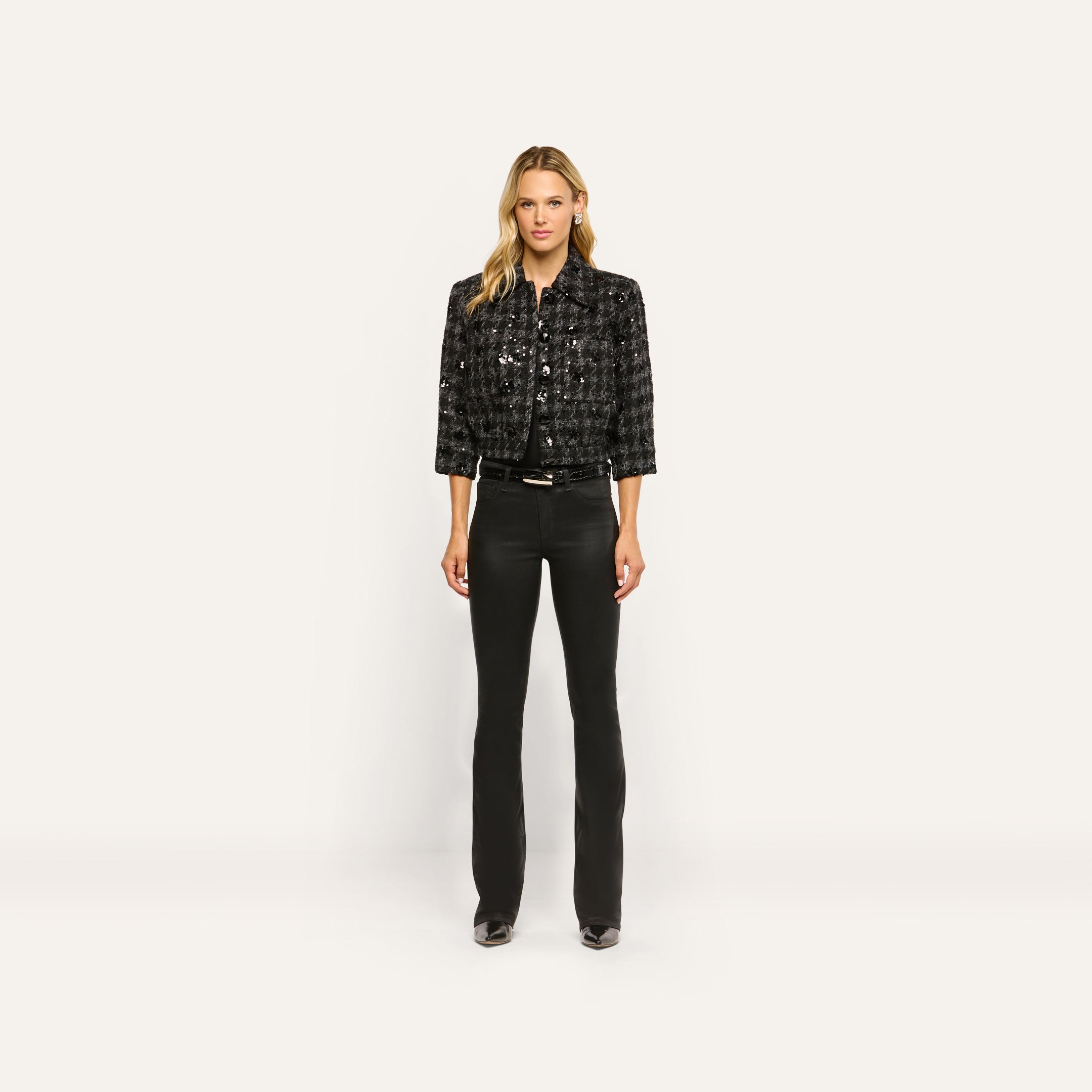 A woman wearing a black Jia Sequined Tweed Jacket, a black shirt, and slim black pants.