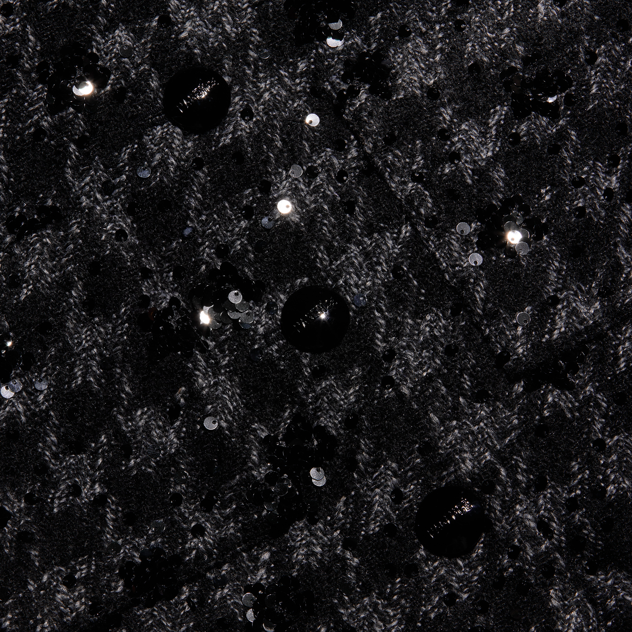 Black tweed fabric of a Jia Sequined Tweed Jacket with a cropped silhouette, textured knit pattern, and scattered black sequin embellishments.