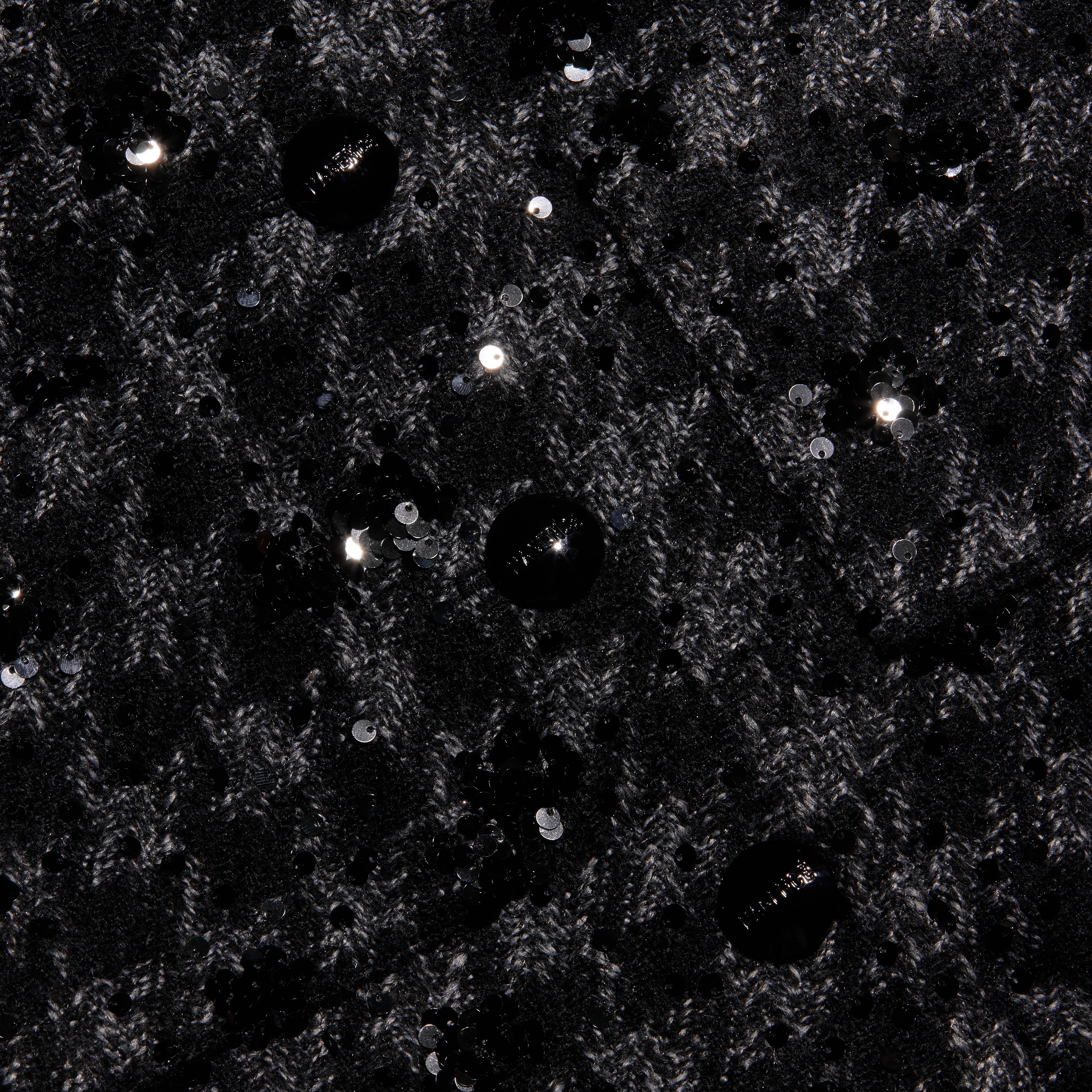 Black tweed fabric of a Jia Sequined Tweed Jacket with a cropped silhouette, textured knit pattern, and scattered black sequin embellishments.