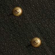 Close-up of two gold lion-embossed buttons on the textured black Zell Tweed Jacket.