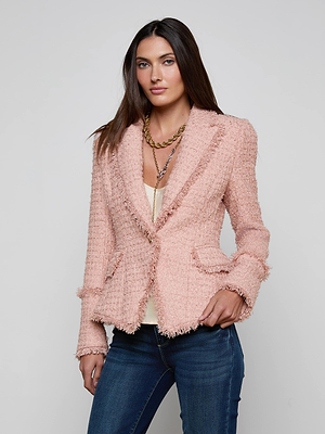 A woman with long brown hair models the L'AGENCE Kaisley Tweed Blazer in pink over a white top and blue jeans, posing with one hand in her pocket against a plain light gray background.