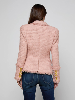 A woman with long brown hair, seen from behind, wears the L'AGENCE Kaisley Tweed Blazer in pink with gold sleeve buttons and blue jeans against a plain light gray background.