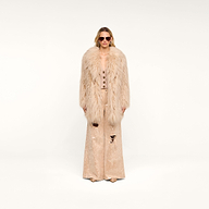 Wearing the Toira Faux Fur Coat, vintage-inspired sunglasses, and matching wide-leg pants with distressed details, a person stands against a plain white background, channeling a 70s rockstar vibe.