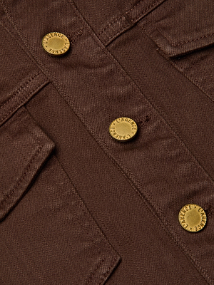 Close-up of the Koda Fringe Jean Jacket in chocolate denim, showing gold metal branded buttons and two chest pockets with flaps. The fabric texture and detailed finishes are clearly visible.