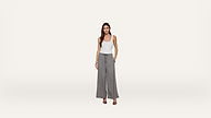 A woman stands against a plain white background, wearing a white tank top, gray wide-leg pants with a drawstring waist, and black heeled sandals. One hand is in her pocket, and she is facing forward, smiling slightly.