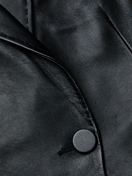 Close-up of the Vashti Fringed Leather Blazer crafted from Italian lambskin leather, highlighting its fine texture, a seam, a lapel, and a single round button.