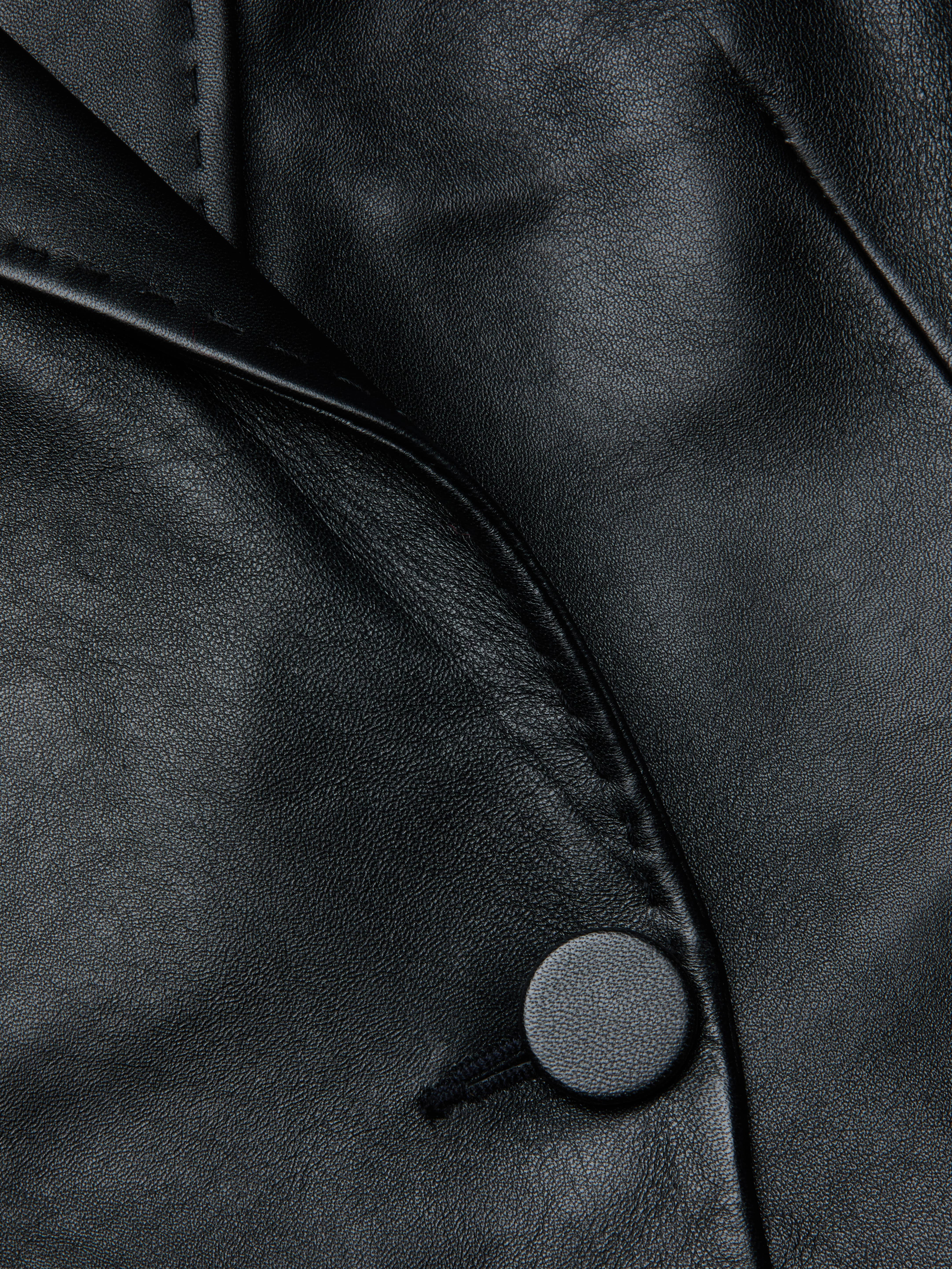 Close-up of the Vashti Fringed Leather Blazer crafted from Italian lambskin leather, highlighting its fine texture, a seam, a lapel, and a single round button.