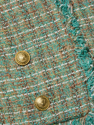Close-up of the L'AGENCE Sale Clydie Cropped Tweed Jacket in green and brown, featuring two gold-tone buttons, frayed edge trim, and a collarless neckline.