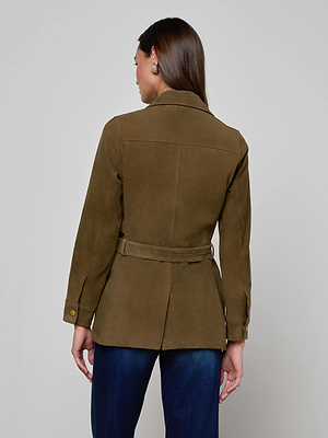 A woman with long brown hair is seen from the back wearing the Ishani Suede Jacket in olive green and dark blue jeans, standing against a plain light gray background.