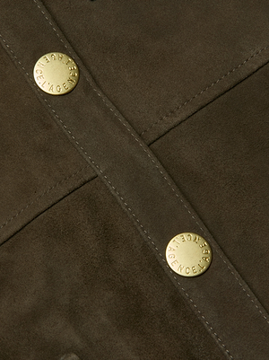 Close-up of the Ishani Suede Jacket in rich brown, featuring a suede belt, two gold engraved snaps, and detailed diagonal and vertical stitching for a refined luxury look.
