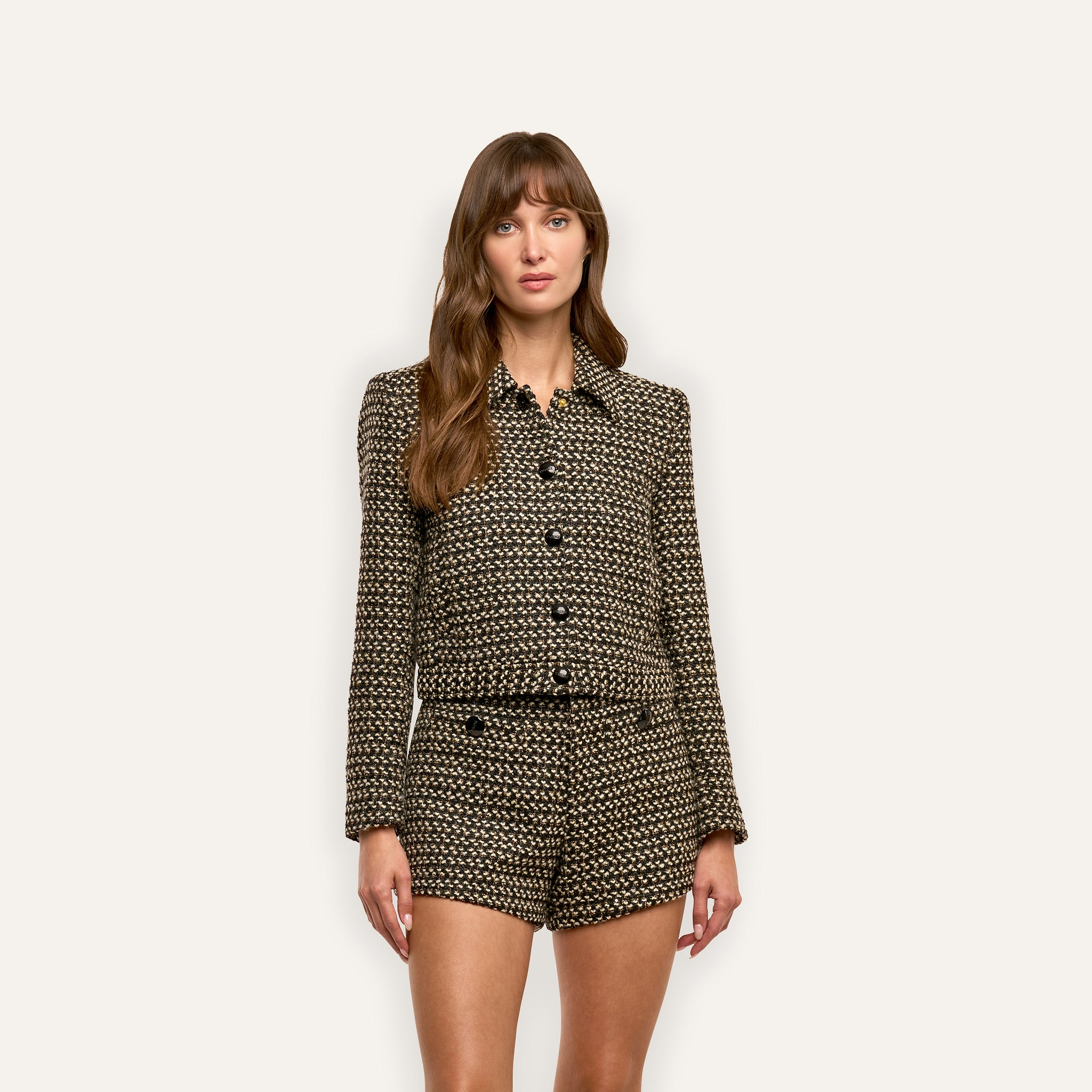 A woman wears a Marla Cropped Jacket and matching shorts made of black and tan textured wool-blend tweed fabric.