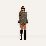 A person wearing a patterned wool-blend tweed Marla Cropped Jacket with matching shorts and knee-high boots.