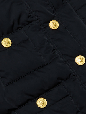 Close-up of the Juana Scarf Puffer Jacket in black, featuring quilted fabric and four shiny gold crest-embossed buttons in two rows. The design exudes glamour and may include a detachable scarf.