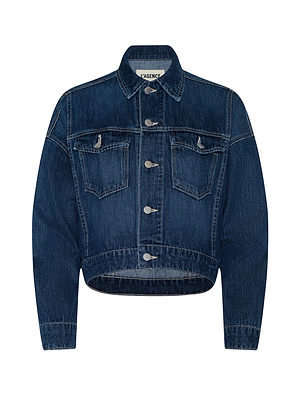 The Vianney Jean Jacket features a dark indigo wash, long sleeves, front button closure, two chest flap pockets, contrast stitching, and a slightly curved cropped hem.