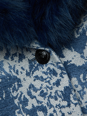 Close-up of the Laney Jacquard Coat by L'AGENCE, featuring textured blue and white fabric, a black button, and a dark blue faux fur collar for vintage-inspired outerwear style.