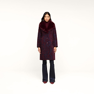 A woman stands facing forward against a plain white background, wearing the Laney Jacquard Coat featuring a vintage-inspired design with a large burgundy faux fur collar, paired with navy pants and burgundy shoes.