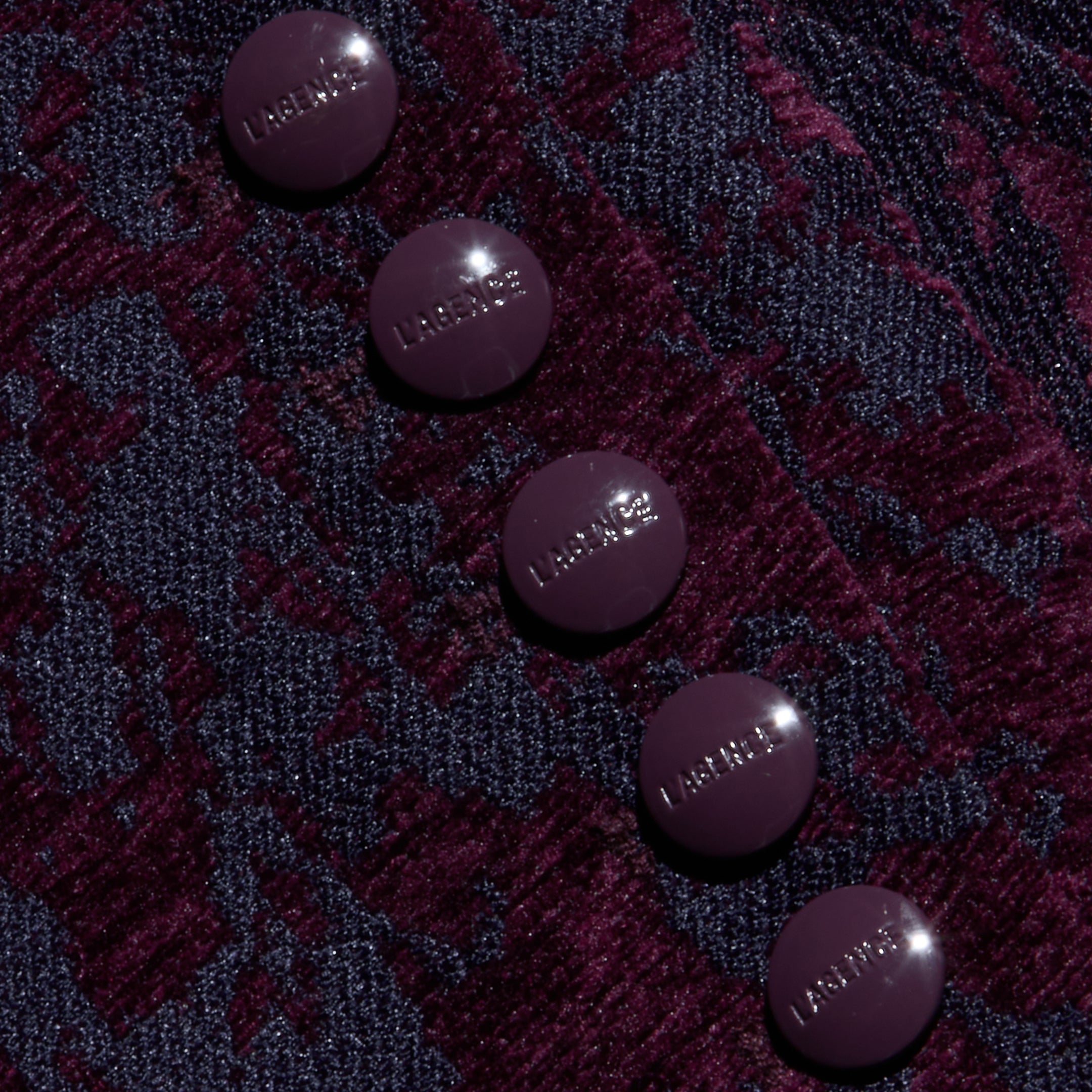 Five round, glossy, dark purple buttons embossed with “LAGENCE” sit atop the textured, burgundy and navy jacquard fabric of the Laney Jacquard Coat, evoking vintage-inspired outerwear.
