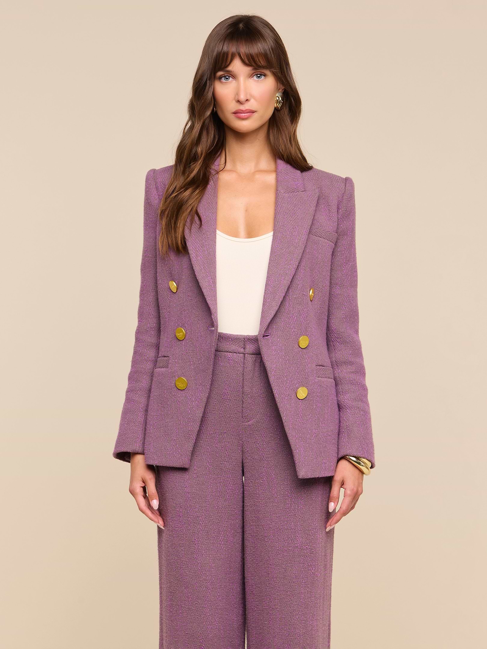 A woman stands facing forward against a plain off-white background, wearing the Kyomi Double-Breasted Blazer in mauve with gold buttons, styled with matching wide-leg pants over a cream top.