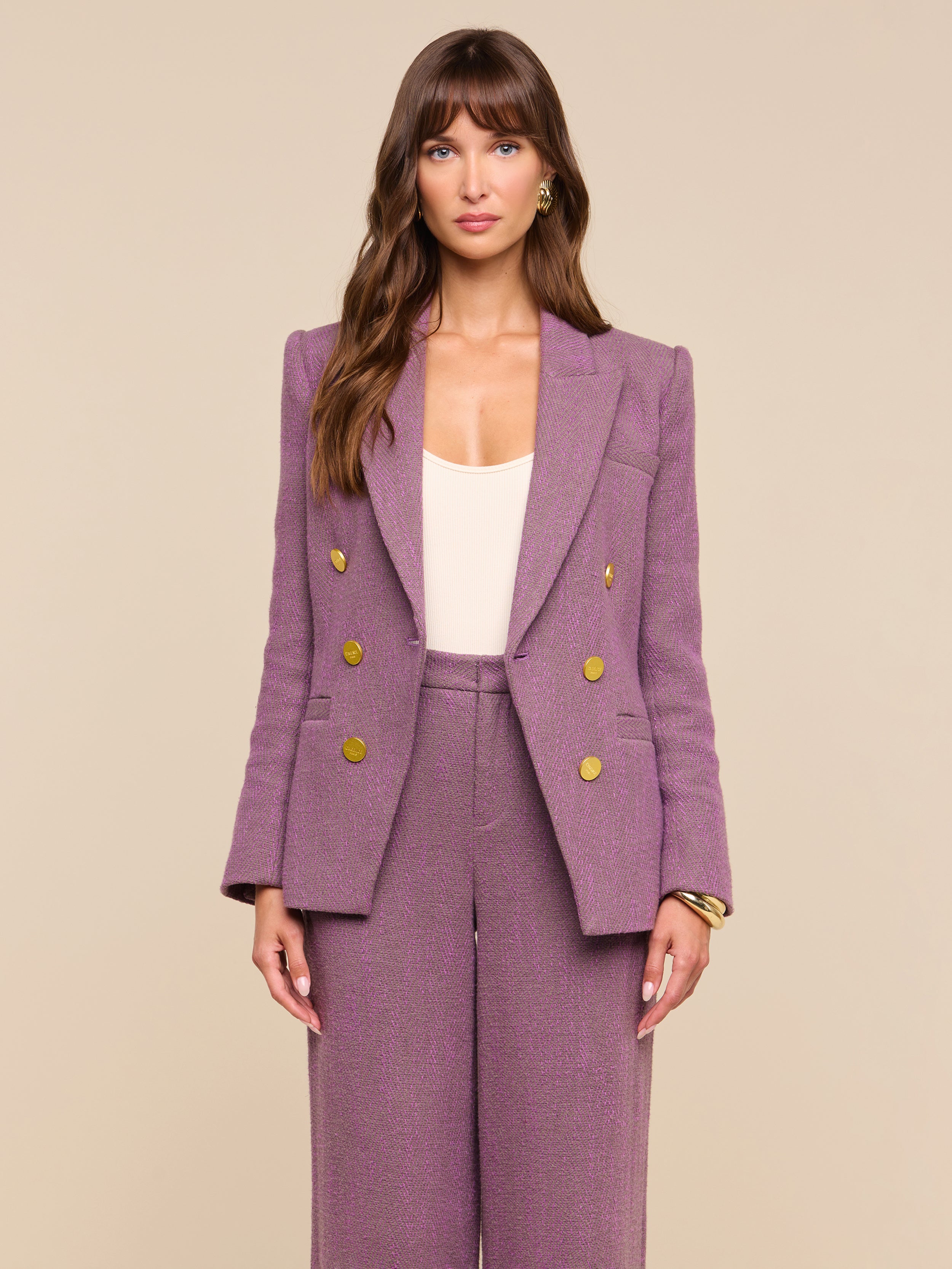 A woman stands facing forward against a plain off-white background, wearing the Kyomi Double-Breasted Blazer in mauve with gold buttons, styled with matching wide-leg pants over a cream top.