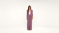 A woman stands in the center, wearing a purple pantsuit, white top, sunglasses, and heels, against a plain white background.