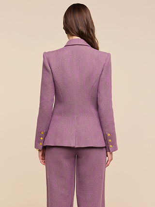 A person with long brown hair is shown from the back against a plain beige background, wearing the Kyomi Double-Breasted Blazer in purple herringbone with gold buttons, styled as part of a tailored suit.