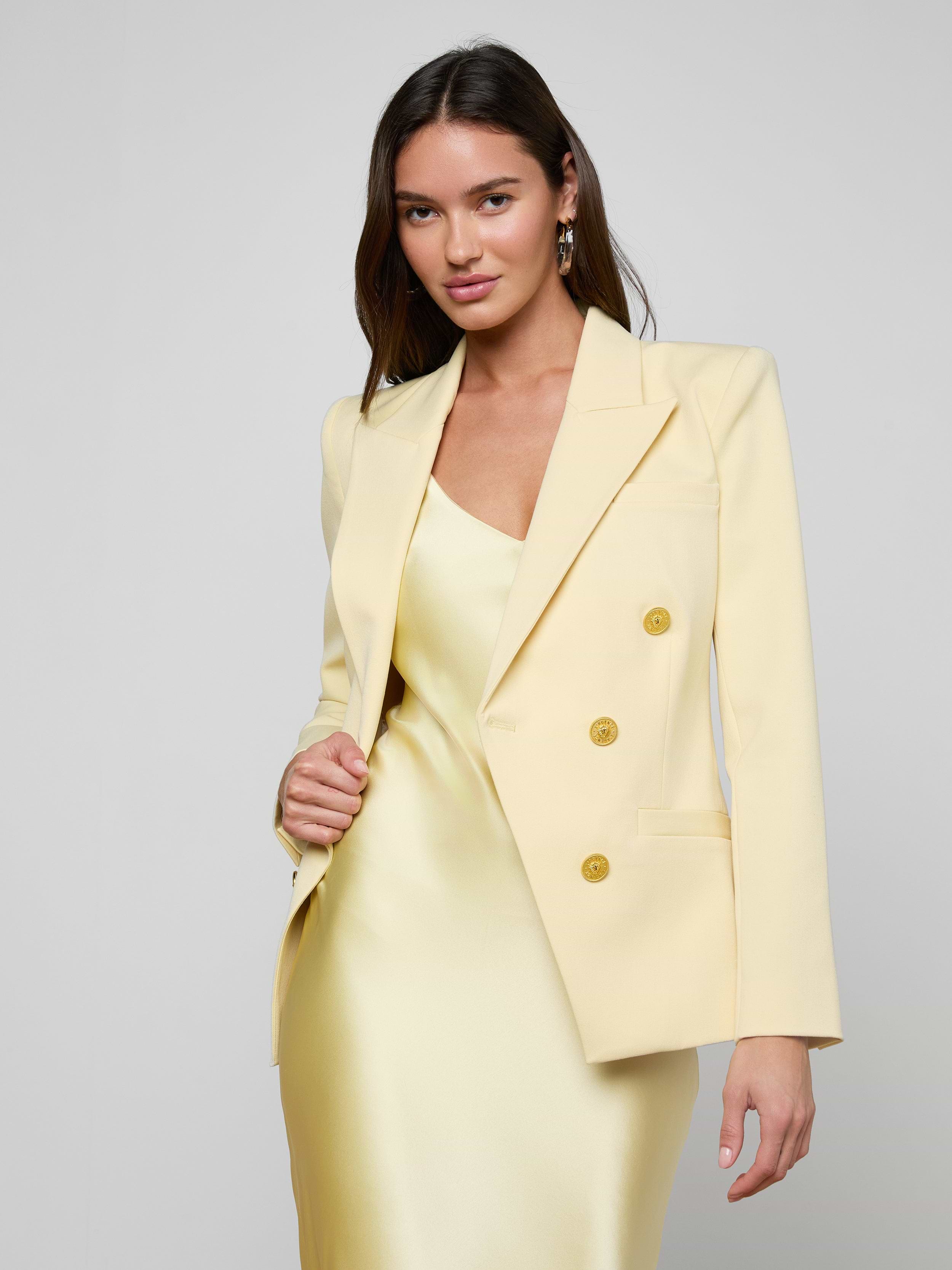 Wearing the Kyomi Double-Breasted Blazer over a matching satin dress, a woman stands confidently against a plain light background, looking directly at the camera.