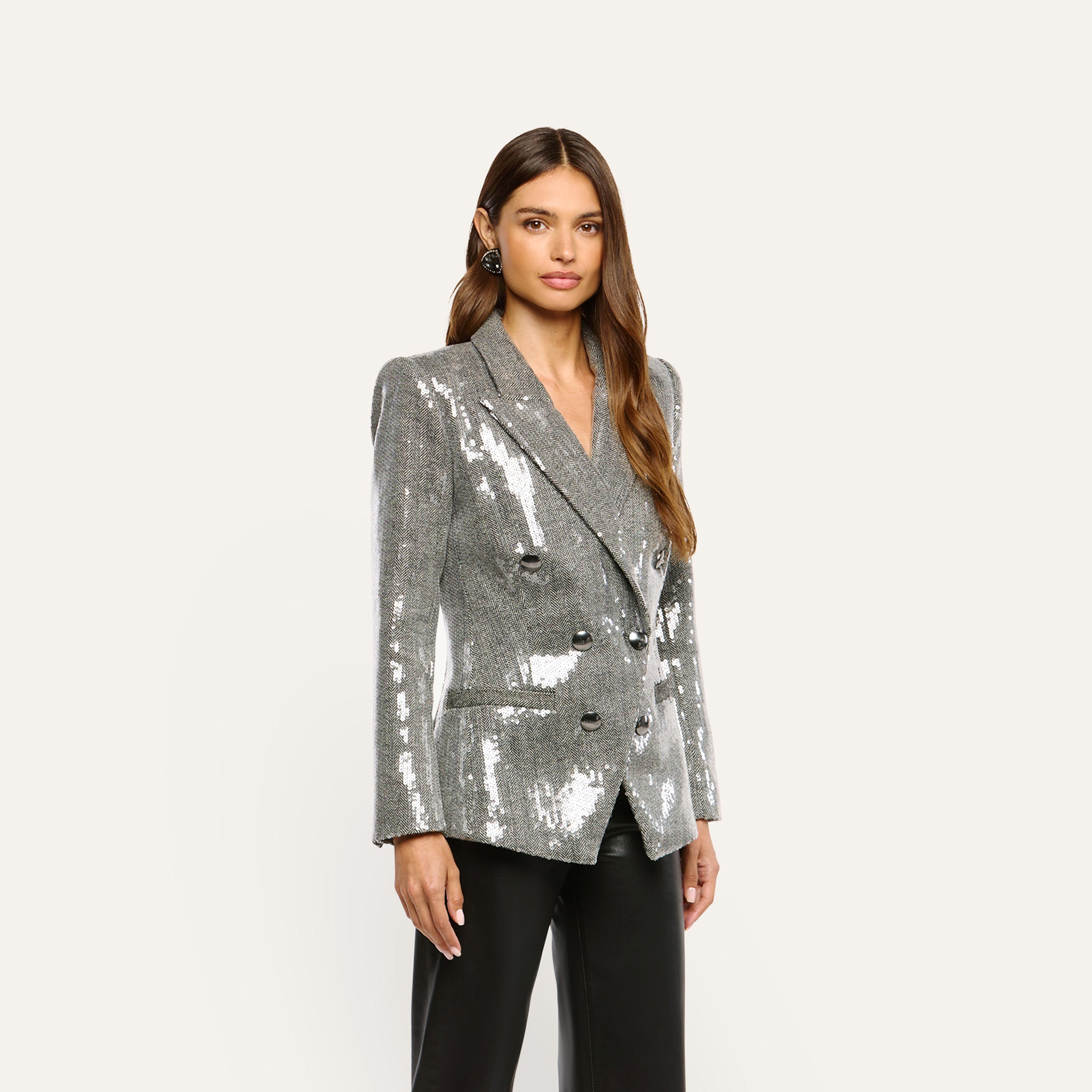 A person wearing a Kyomi Sequined Blazer, a double-breasted, silver sequined blazer, over black trousers.