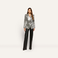 A woman wearing a Kyomi Sequined Blazer in silver with a double-breasted design and black wide-leg trousers.