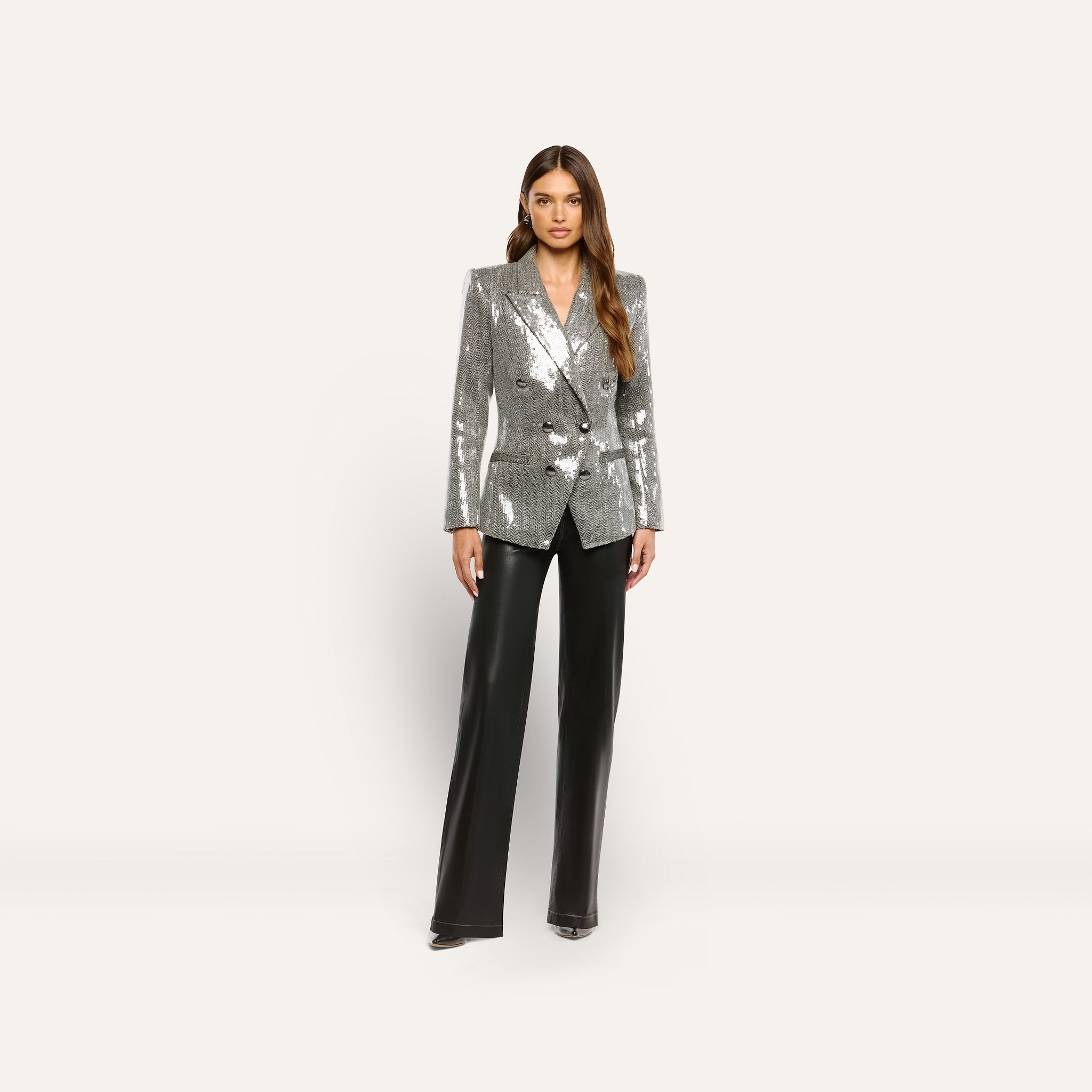 A woman wearing a Kyomi Sequined Blazer in silver with a double-breasted design and black wide-leg trousers.