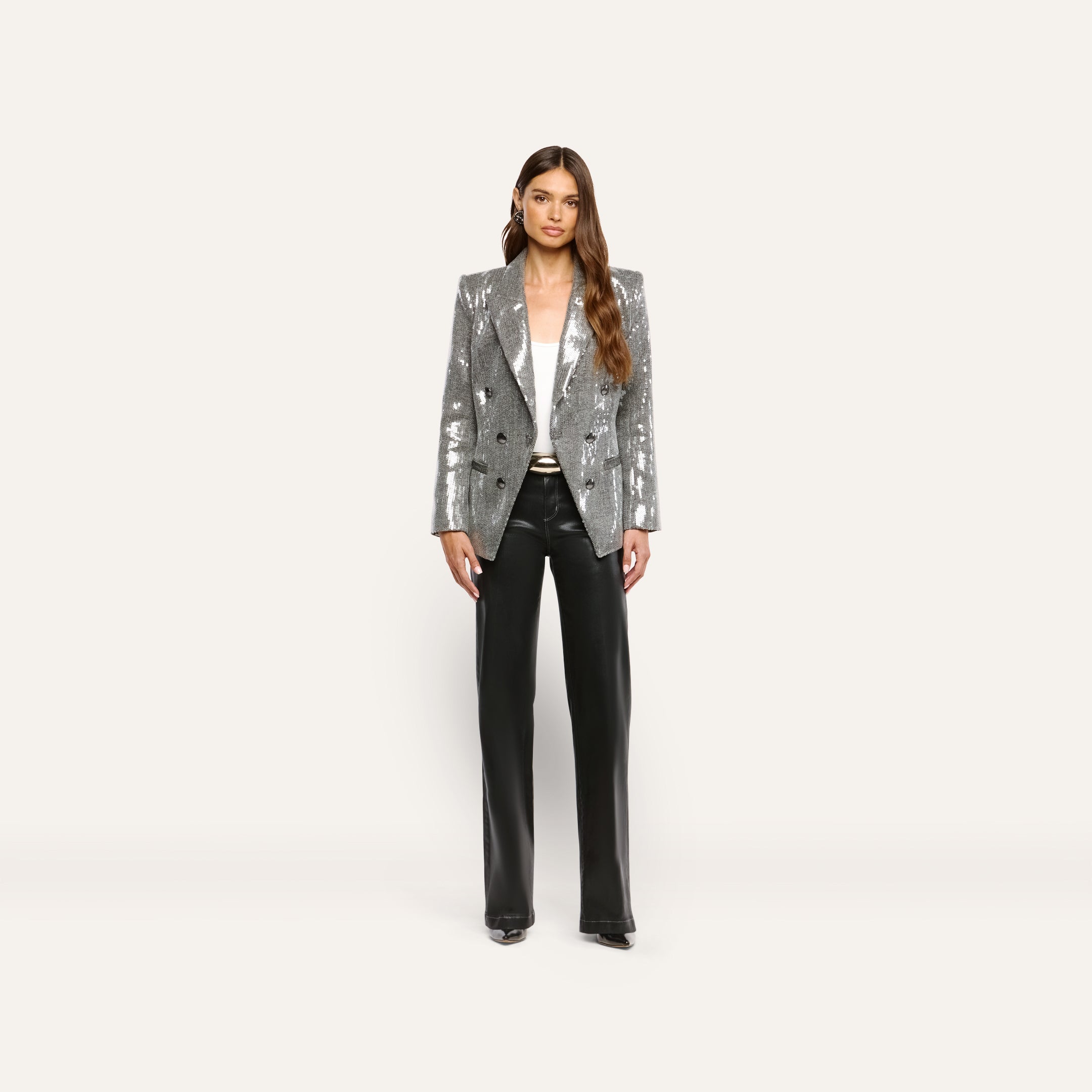 A woman wearing a silver sequined Kyomi Sequined Blazer over a white top and black trousers.