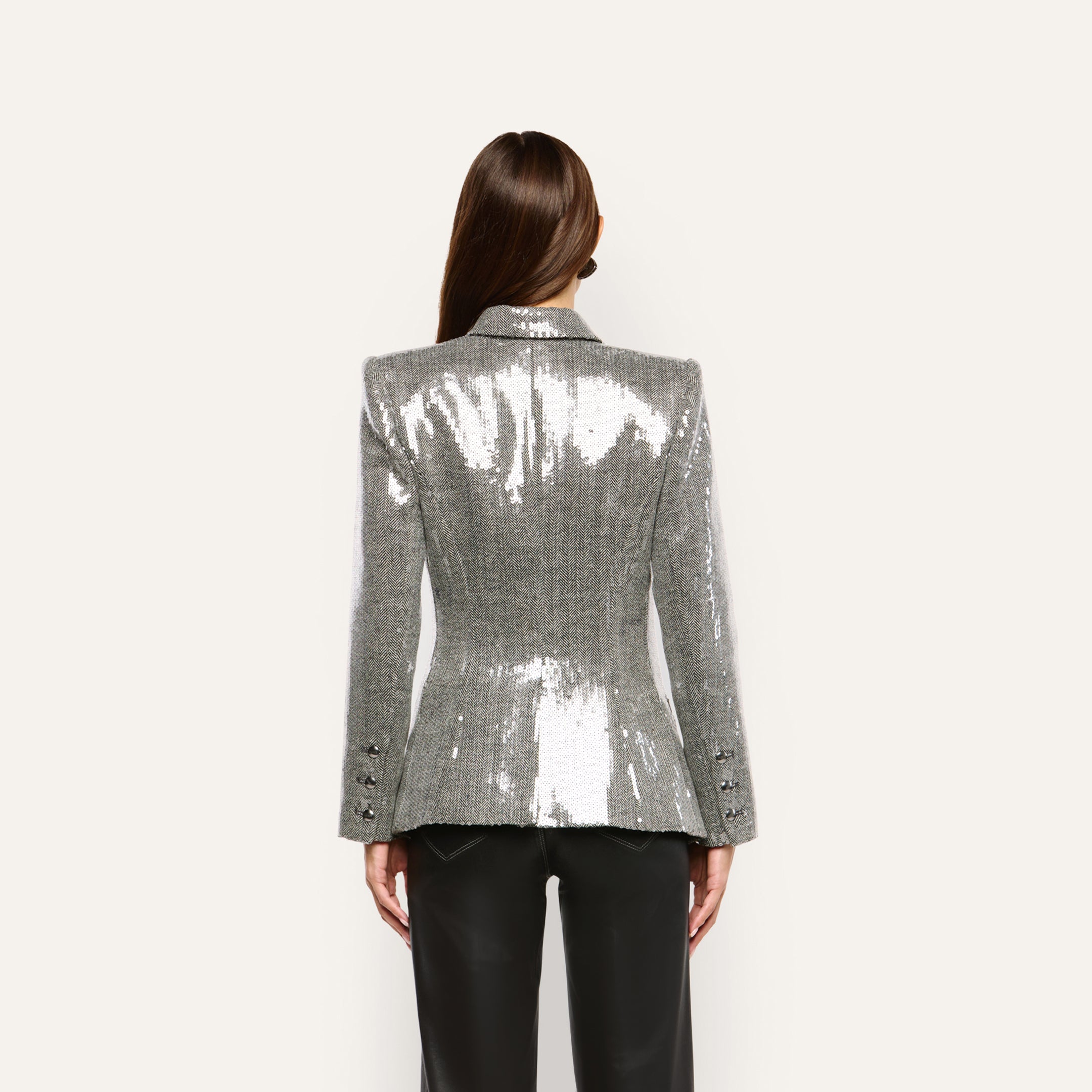 Back view of a person wearing a silver, double-breasted Kyomi Sequined Blazer with structured shoulders and black trousers.