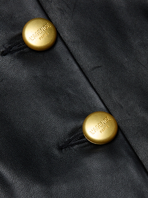 Close-up of the Mariella Leather Jacket in black lambskin, showcasing two round gold buttons engraved with LACENUR and PARIS, attached with black thread.