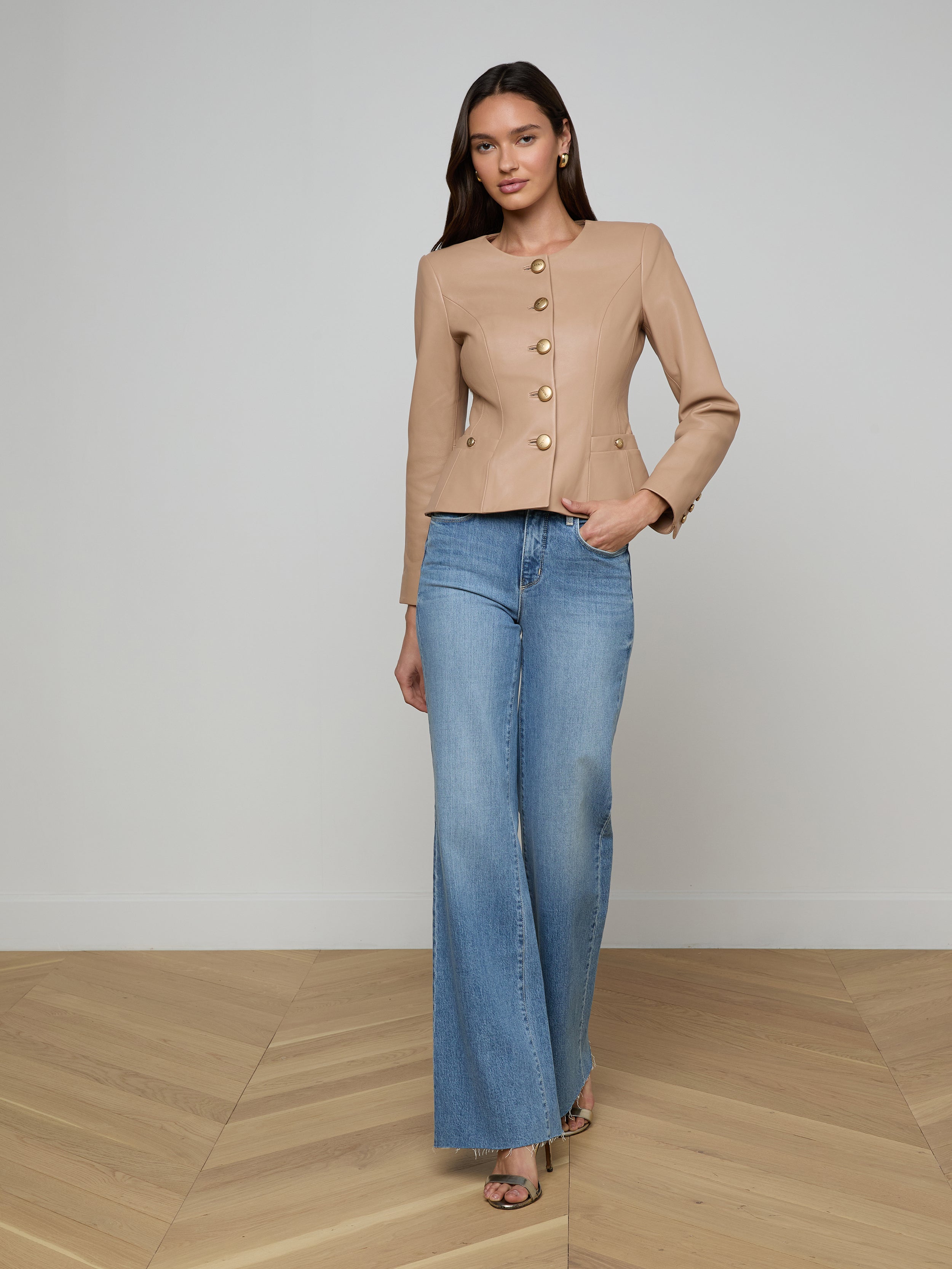 Woman in the Mariella Leather Jacket and wide-leg blue jeans, standing and facing forward against a plain white background.