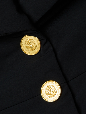 Close-up of the Pippa High Collar Jacket in black, featuring a cinched silhouette and two gold decorative buttons with embossed wreaths and text around the edge.