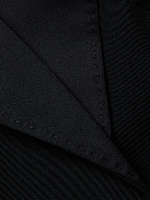 Close-up of the Daxton Cropped Blazer by L'AGENCE in black fabric, featuring visible stitching and a satin lapel overlap on the collar—highlighting its smooth, tailored texture ideal for sophisticated eveningwear.