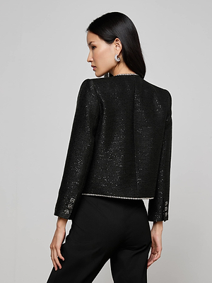 A woman with long dark hair is seen from the back wearing the L'AGENCE Zell Sequined Tweed Jacket and matching black pants, set against a plain light gray background.