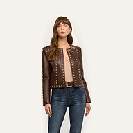 A woman wearing a cropped chocolate brown Fia Leather Jacket embellished with gold studs along the neckline and sleeves.