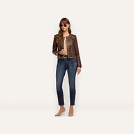 A woman wears a chocolate brown, studded Fia Leather Jacket paired with dark blue jeans and tan high-heeled pumps.