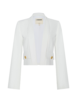 The Nixie Cardigan Jacket is a white, tailored, cropped blazer with long sleeves, peaked lapels, and gold front buttons in fluid suit fabric. The inner label reads LAGENCE.